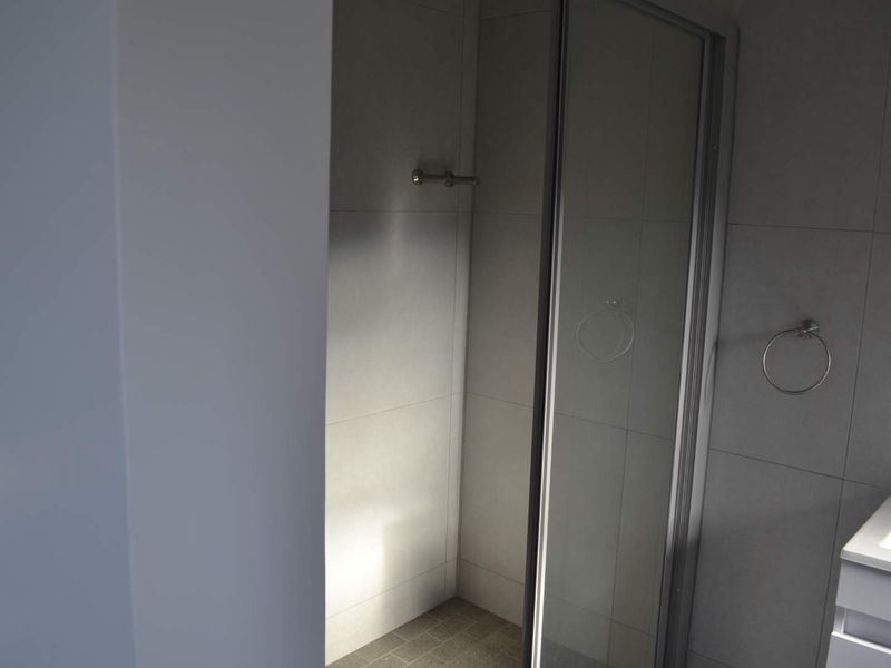 A modern bathroom featuring a glass-enclosed shower, tiled walls, and a vanity basin with integrated storage.
