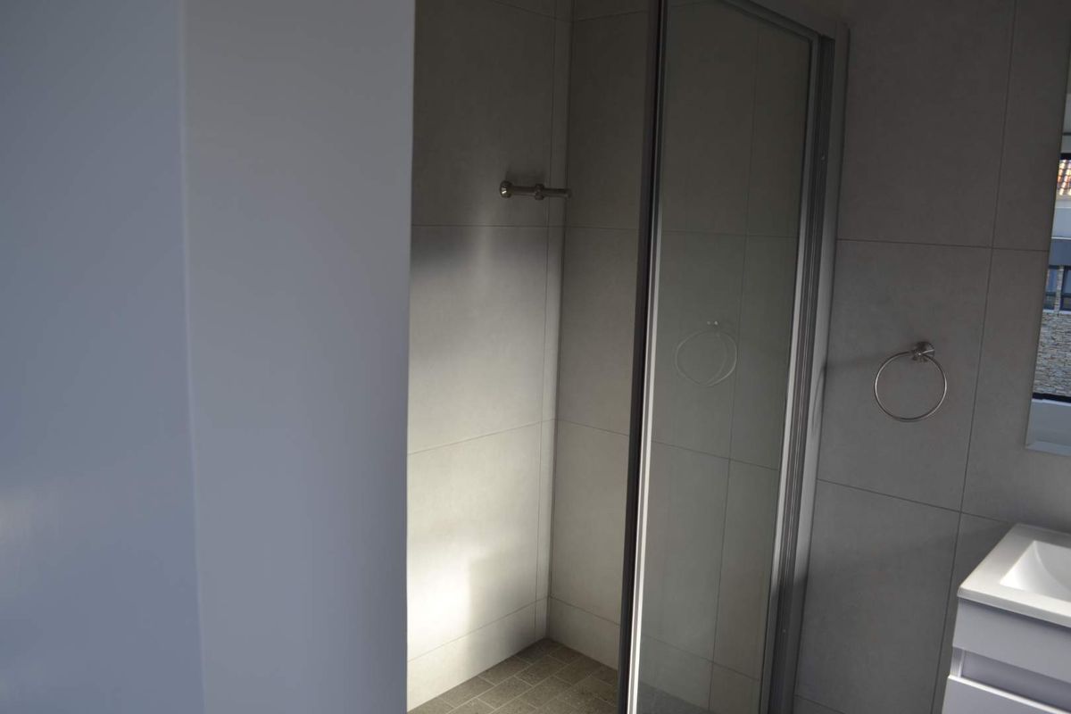 A modern bathroom featuring a glass-enclosed shower, tiled walls, and a vanity basin with integrated storage.