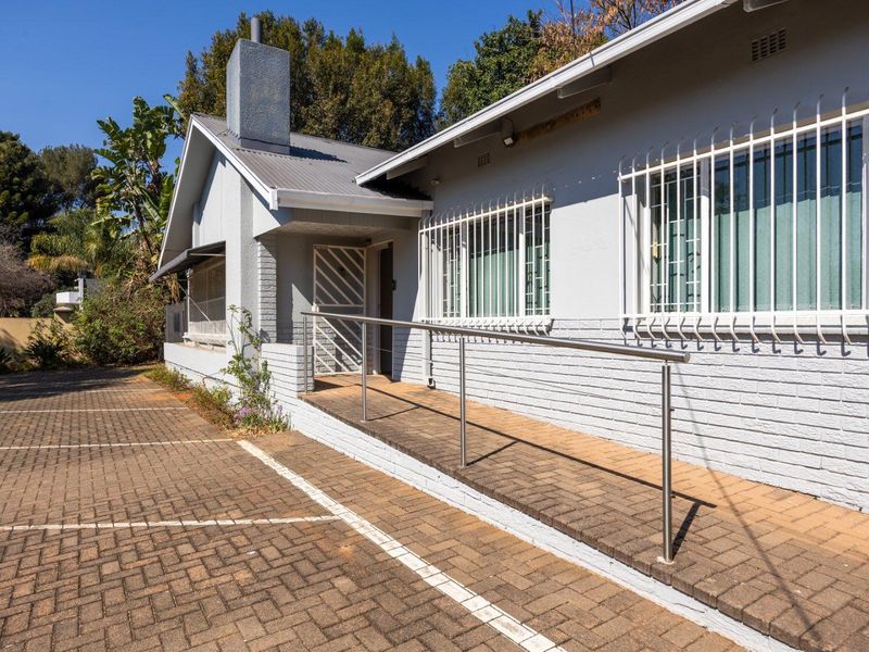 Front exterior view of the property featuring a paved driveway, wheelchair access ramp with stainless steel handrail, and security bars on windows.