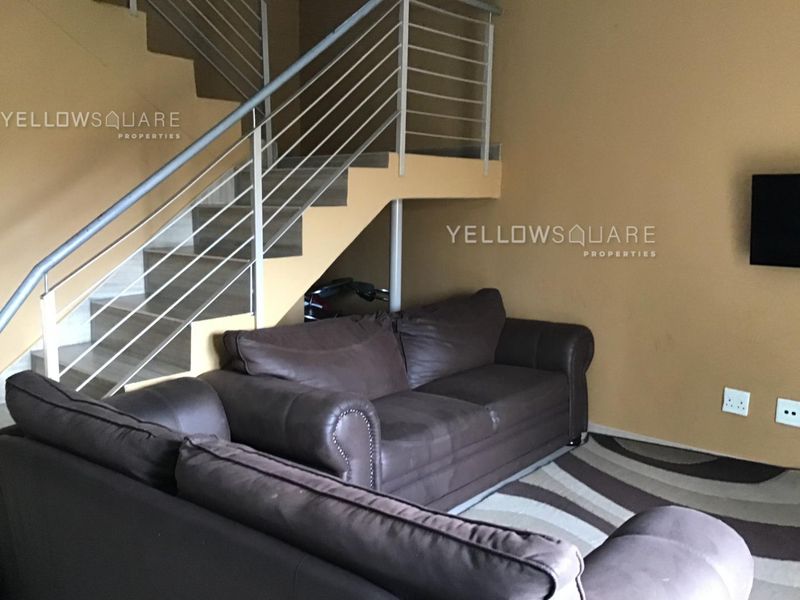 A living room area featuring a staircase with a metal balustrade and neutral wall finishes.