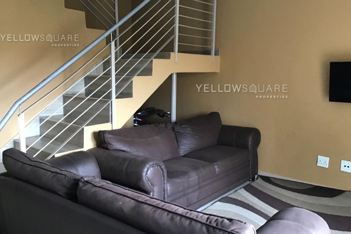 A living room area featuring a staircase with a metal balustrade and neutral wall finishes.