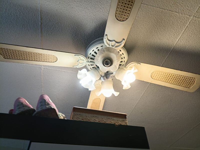 A close-up view of a vintage-style ceiling fan with integrated light fixtures mounted on a textured ceiling.