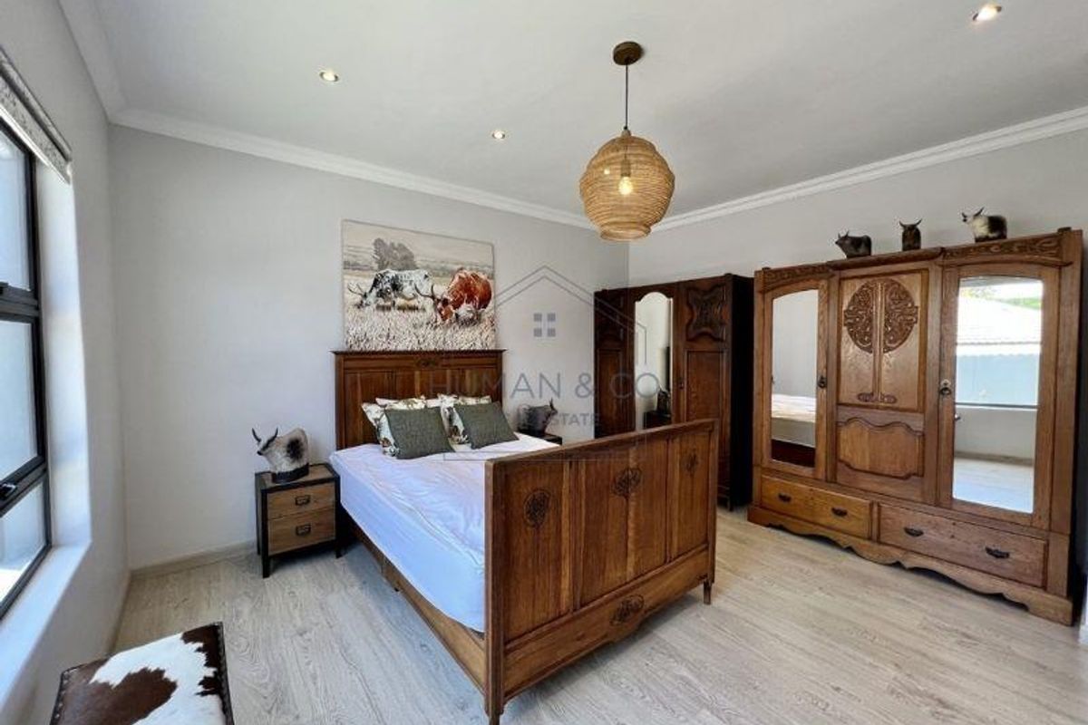 A well-maintained bedroom featuring light-toned laminate flooring, recessed ceiling lighting, and a neutral color palette.