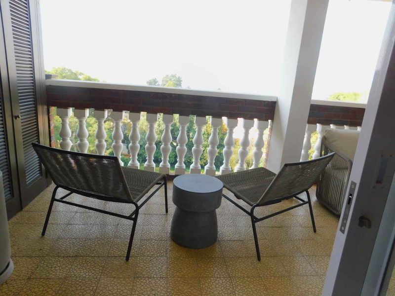 A covered balcony featuring a decorative balustrade, tiled flooring, and access via a sliding door, offering an outdoor space for relaxation.