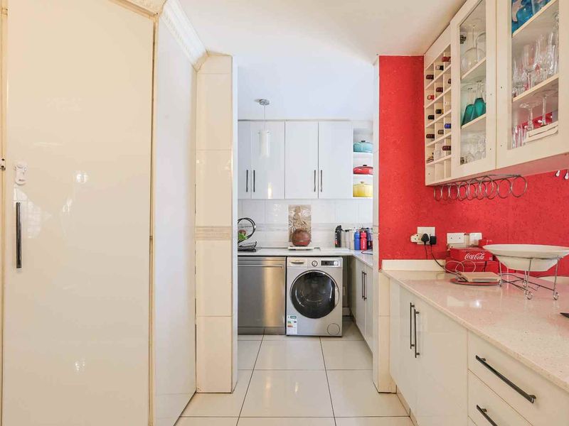 A functional scullery area featuring built-in cabinetry, stone countertops, integrated wine storage, and dedicated spaces for a washing machine and dishwasher.