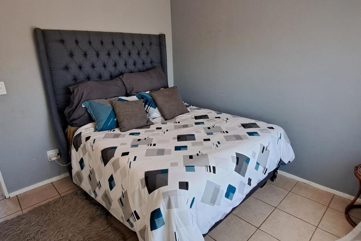 A bedroom featuring tiled flooring and neutral wall paint, with an adjacent view into a bathroom area.