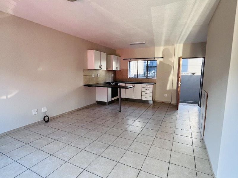 An open-plan living and kitchen area featuring tiled flooring, built-in cabinetry, and direct access to an outdoor space.