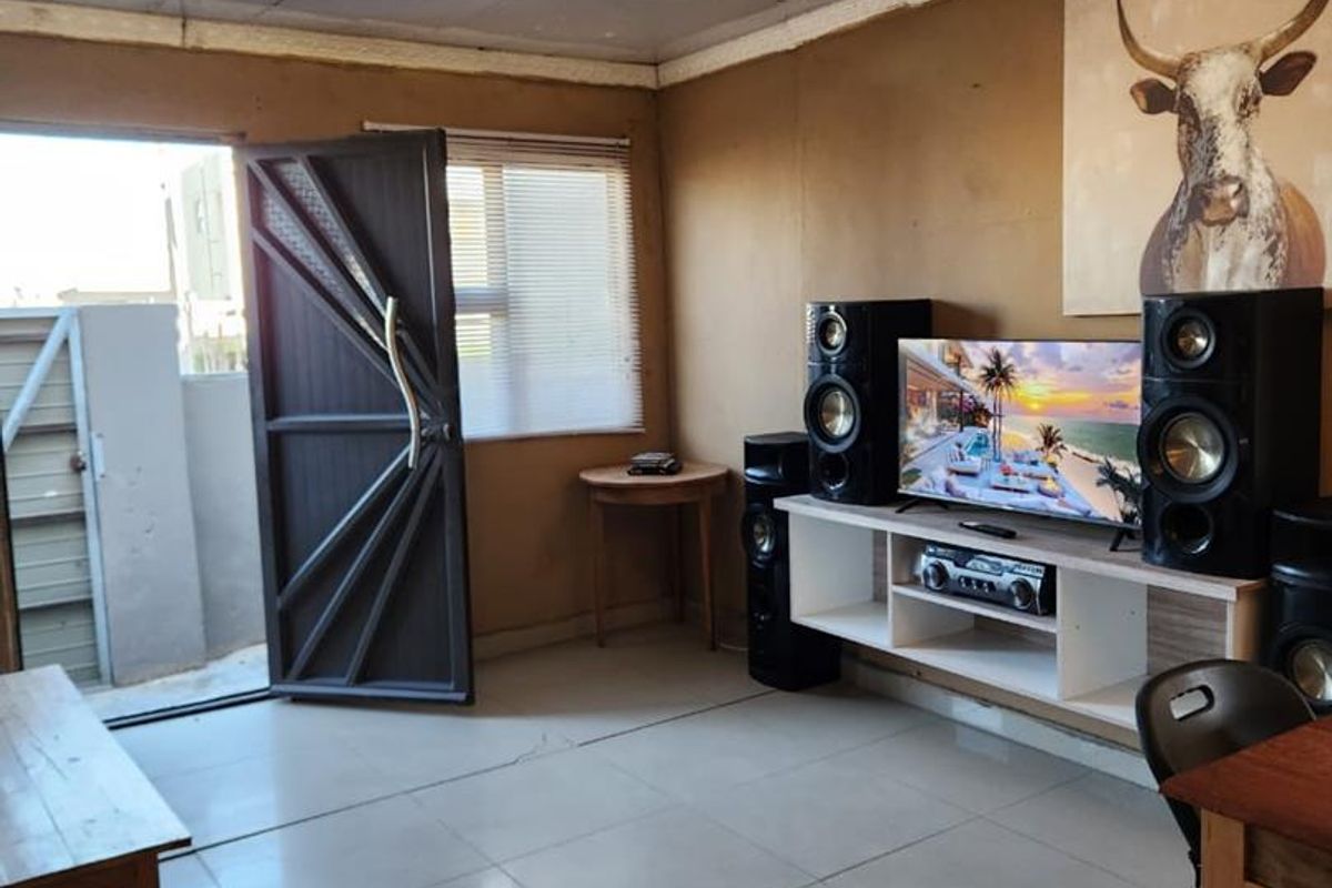 A living room featuring tiled flooring, a security door leading to the exterior, and a built-in media console area.