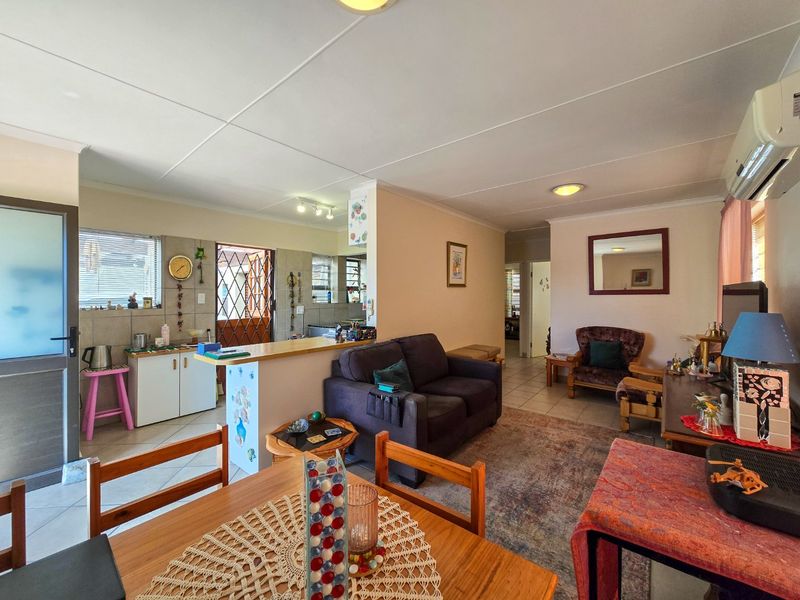 Open plan living and kitchen area featuring tiled flooring, a breakfast bar, and a wall-mounted split system air conditioner.