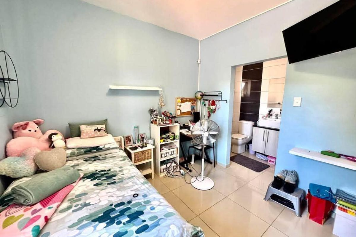 A bedroom featuring tiled flooring and an attached en-suite bathroom with a vanity and toilet.