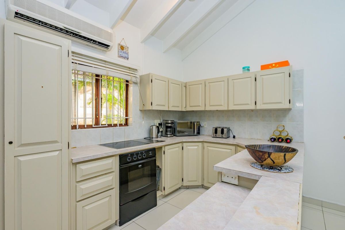 A functional kitchen featuring built-in cabinetry, an electric oven and hob, tiled backsplash, and a split-system air conditioner for climate control.