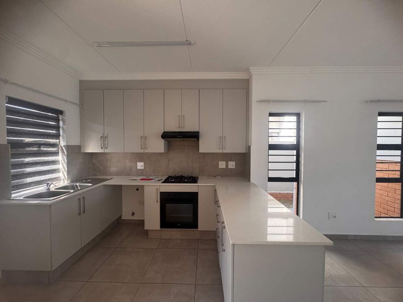 Modern kitchen featuring neutral cabinetry, stone countertops, integrated gas hob, electric oven, and tiled flooring in a clean, open-plan layout.