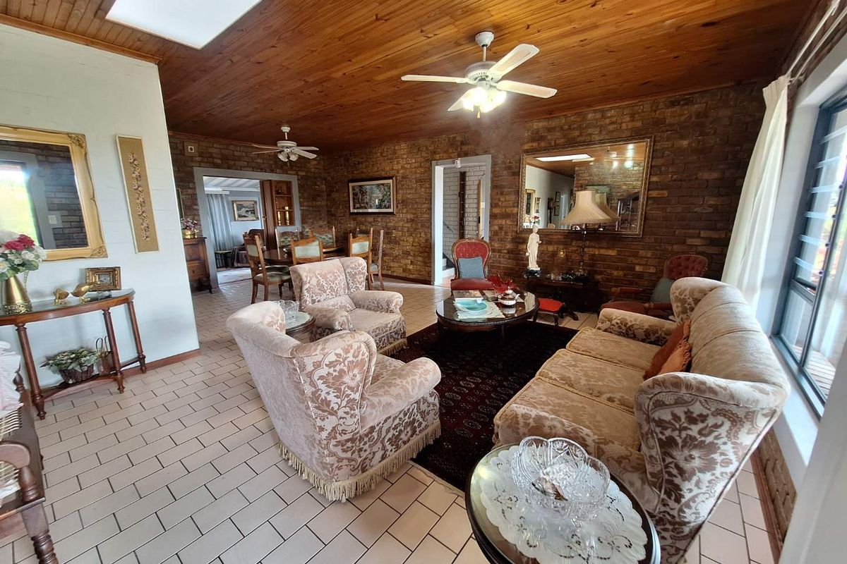 Spacious living area featuring exposed brick walls, timber-clad ceiling with skylight, and tiled flooring, offering a warm and traditional aesthetic.