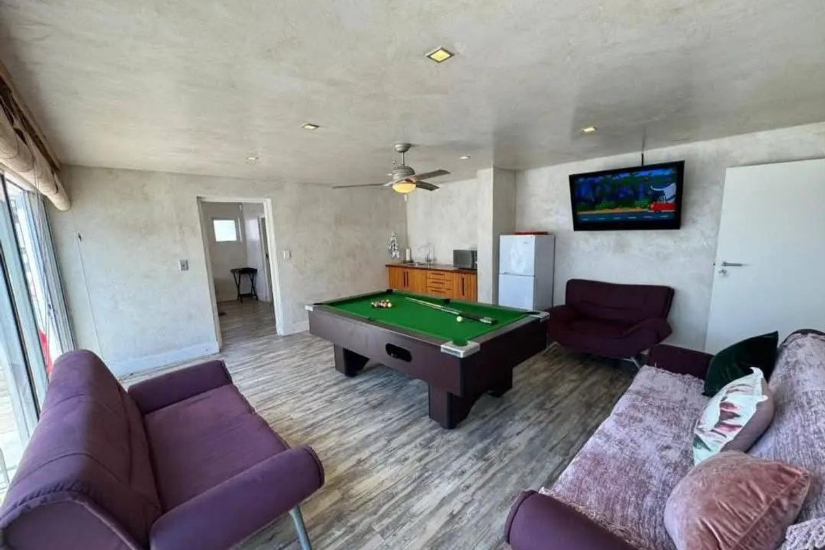 Spacious living area featuring wood-look flooring, recessed ceiling lighting, and a ceiling fan, currently utilized as a recreational space.