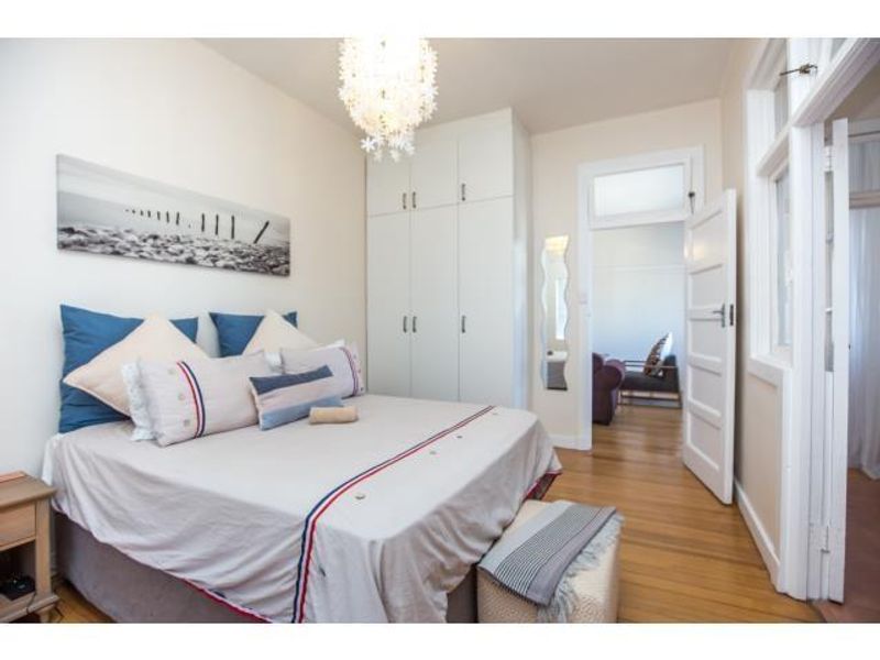 A well-maintained bedroom featuring hardwood flooring, a built-in wardrobe, and a classic panel door with a transom window.