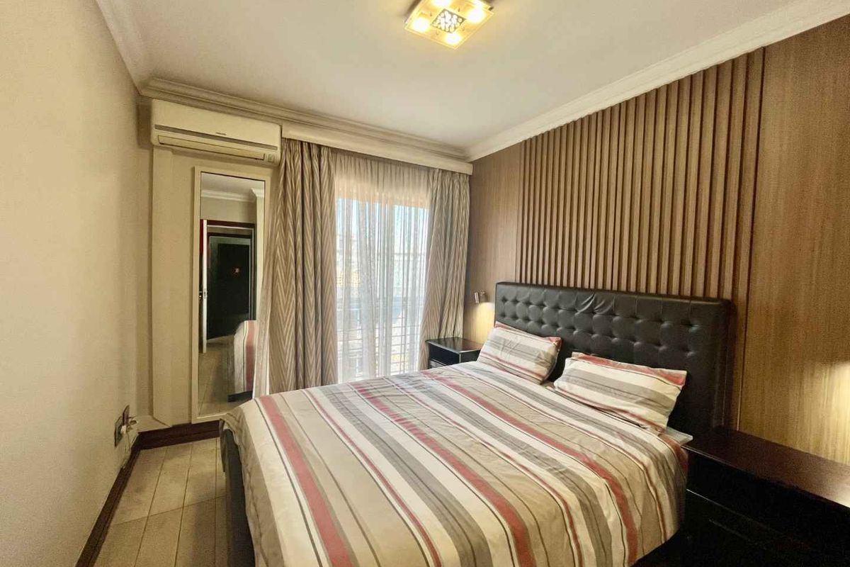 A well-maintained bedroom featuring a decorative timber-slat feature wall, integrated air conditioning unit, and direct access to a balcony through sliding glass doors.