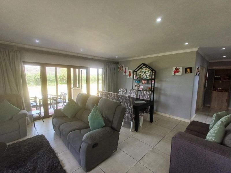 Open-plan living and dining area featuring tiled flooring, recessed downlights, and large sliding glass doors providing access to the outdoor patio.