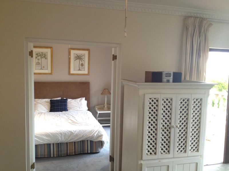 A bedroom featuring crown molding and access to an adjoining space, with neutral wall finishes and carpeted flooring.