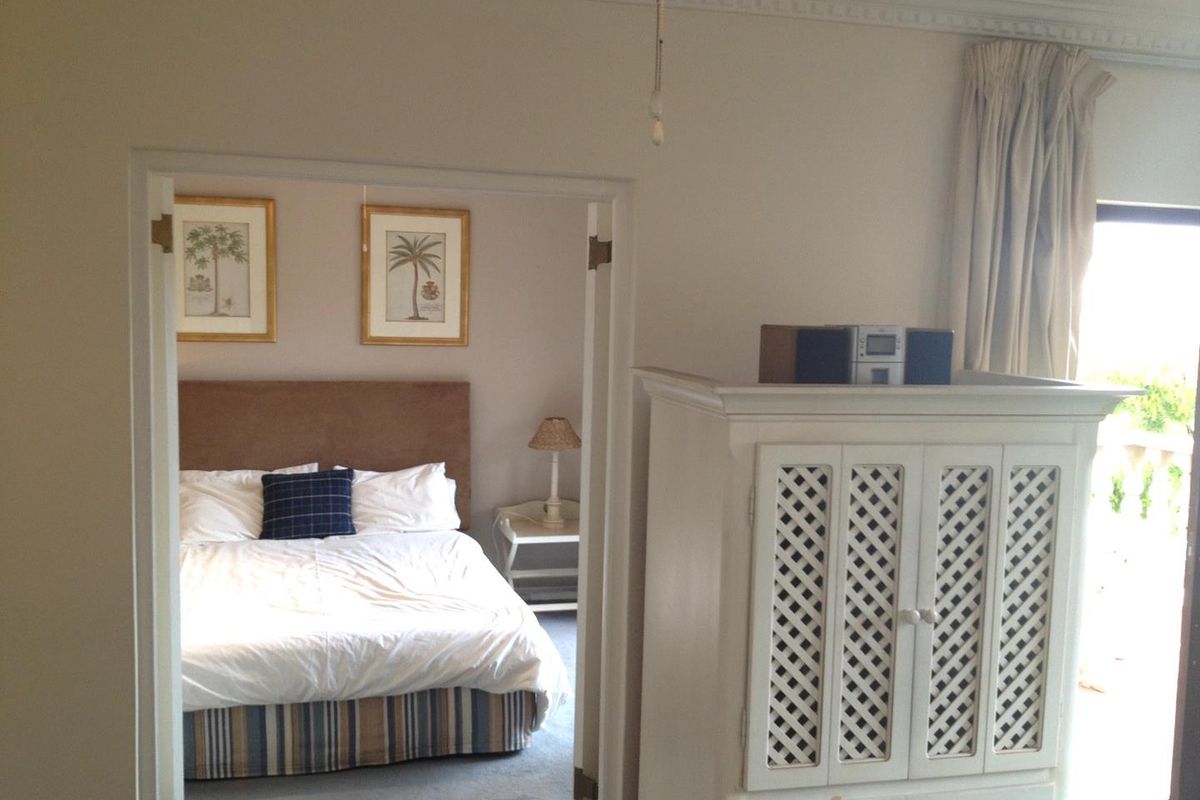A bedroom featuring crown molding and access to an adjoining space, with neutral wall finishes and carpeted flooring.