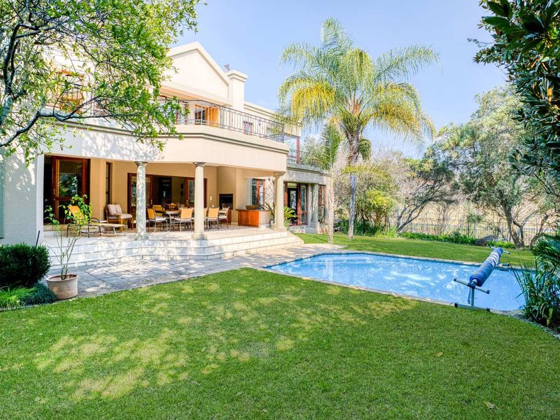 Spacious rear exterior featuring a covered patio with built-in braai, a swimming pool, and a well-maintained garden with a balcony above.