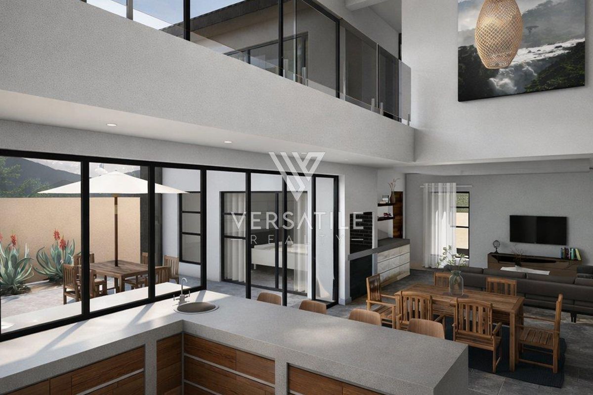 Spacious open-plan living area featuring a modern kitchen with stone countertops, exposed timber beams, and seamless indoor-outdoor flow through large glass sliding doors.