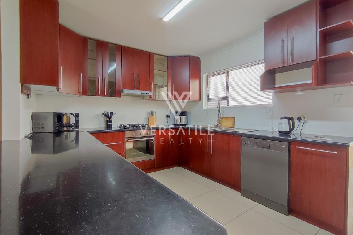 A functional kitchen featuring dark wood cabinetry, granite countertops, a gas hob, built-in oven, and tiled flooring.