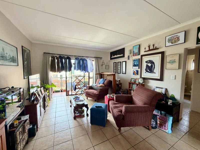 A living room featuring tiled flooring and a sliding glass door providing access to an outdoor balcony area.