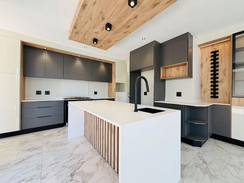 Modern, high-end kitchen featuring dark grey cabinetry, wood-look accents, a central island with quartz countertop, and premium integrated appliances.
