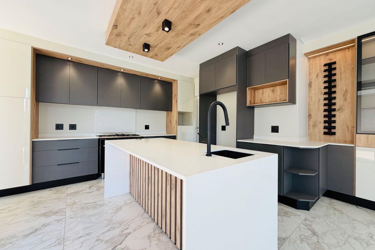 Modern, high-end kitchen featuring dark grey cabinetry, wood-look accents, a central island with quartz countertop, and premium integrated appliances.