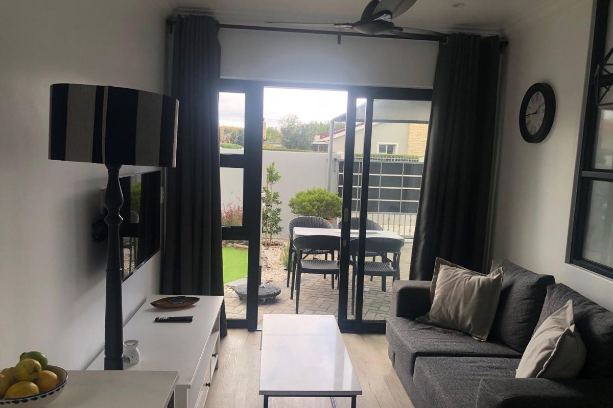 A bright living room featuring sliding glass doors that open onto a paved patio area, creating a seamless indoor-outdoor flow.