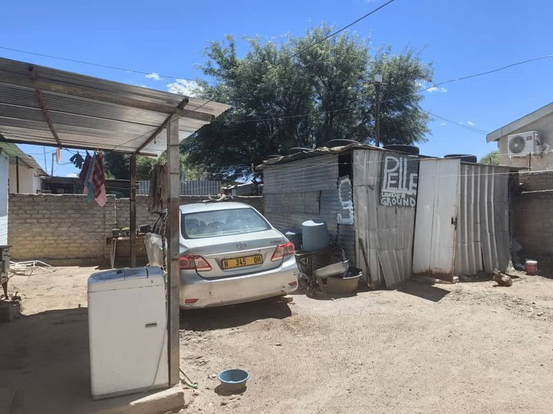 Rear yard area featuring a corrugated iron roof structure, brick boundary walls, and a small corrugated iron storage shed.