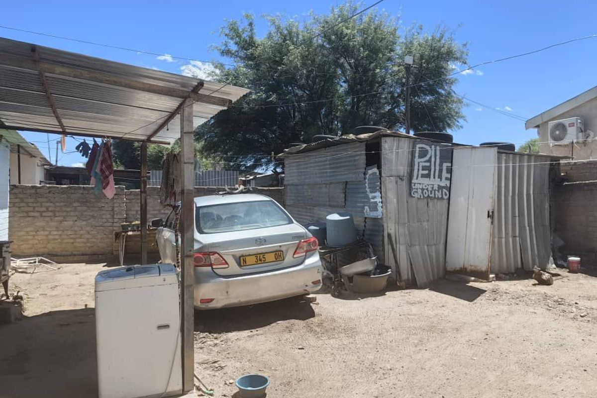 Rear yard area featuring a corrugated iron roof structure, brick boundary walls, and a small corrugated iron storage shed.