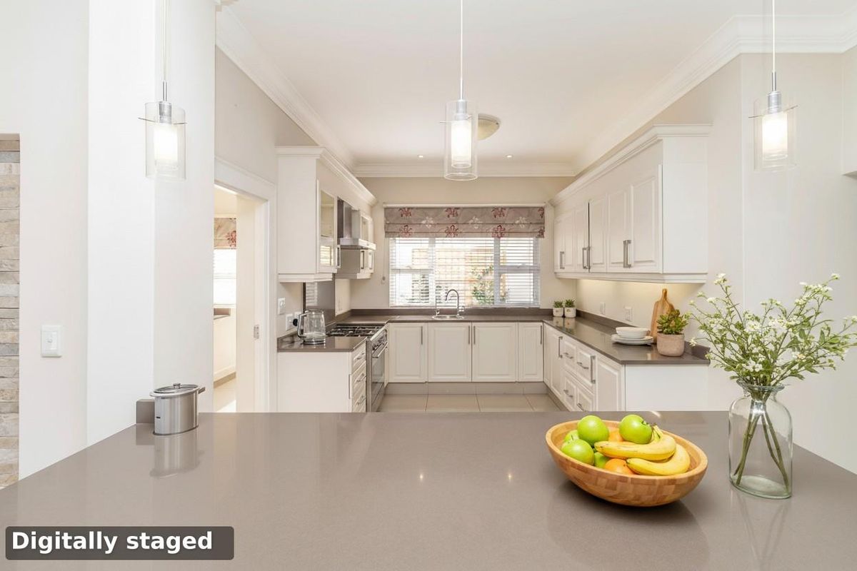 A modern, well-lit kitchen featuring white cabinetry, stone countertops, a built-in gas hob, and an integrated oven with a clean, functional layout.