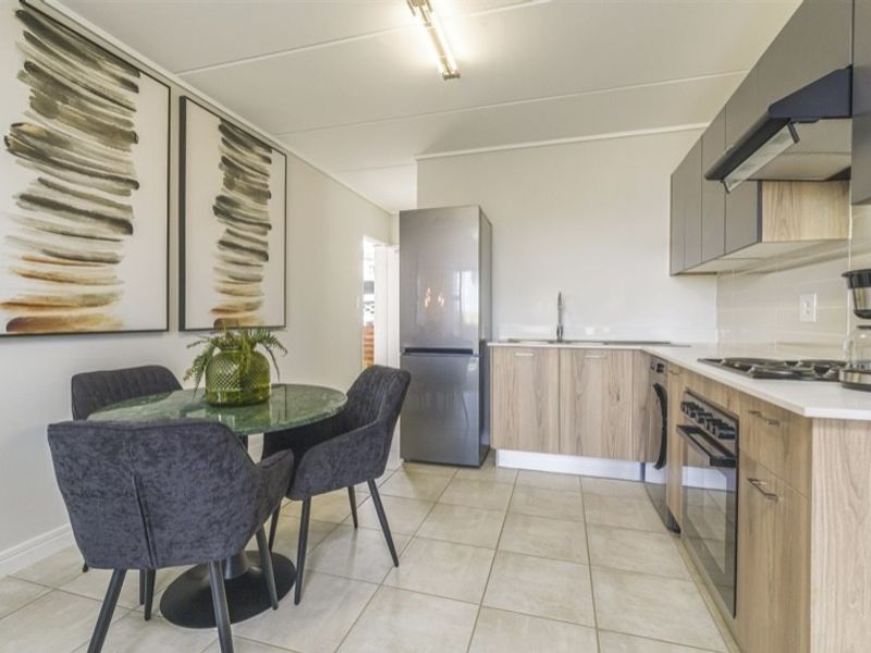 Modern open-plan kitchen and dining area featuring contemporary cabinetry, integrated appliances, and neutral tiled flooring, creating a functional and cohesive living space.
