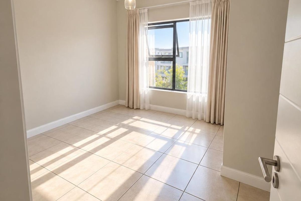 A bright, empty bedroom featuring neutral tiled flooring, a modern pendant light, and large windows allowing for ample natural light.