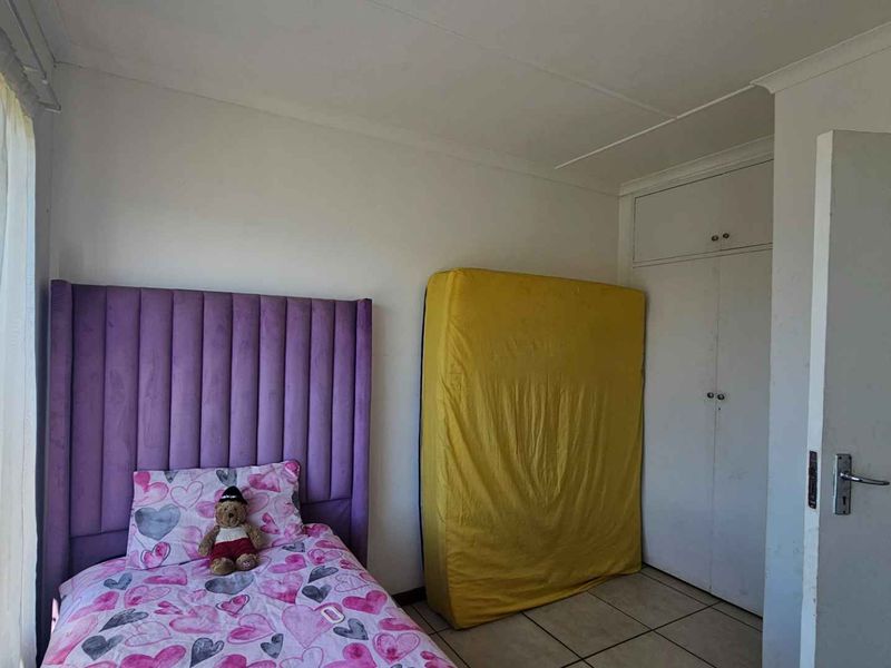 A bedroom featuring tiled flooring and built-in cupboards, providing functional storage space.