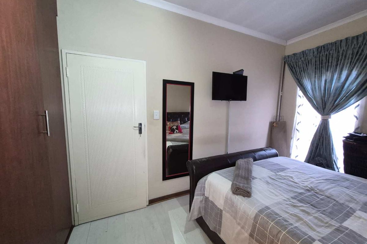 A functional bedroom featuring laminate flooring, a built-in wardrobe, and cove cornice detailing, providing a practical living space.
