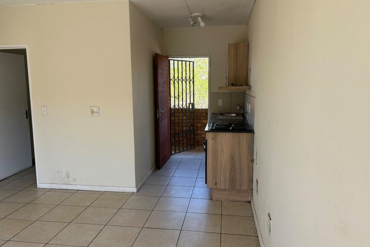 Compact kitchen area featuring built-in cabinetry, a small countertop with a sink and hob, and direct access to an outdoor balcony.
