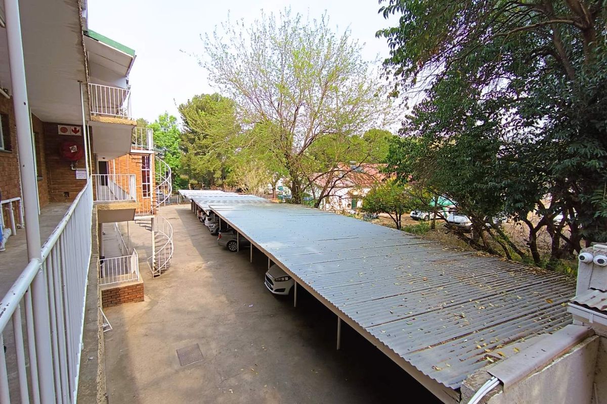 Exterior view of the apartment complex featuring covered parking bays and a metal spiral staircase providing access to upper levels.