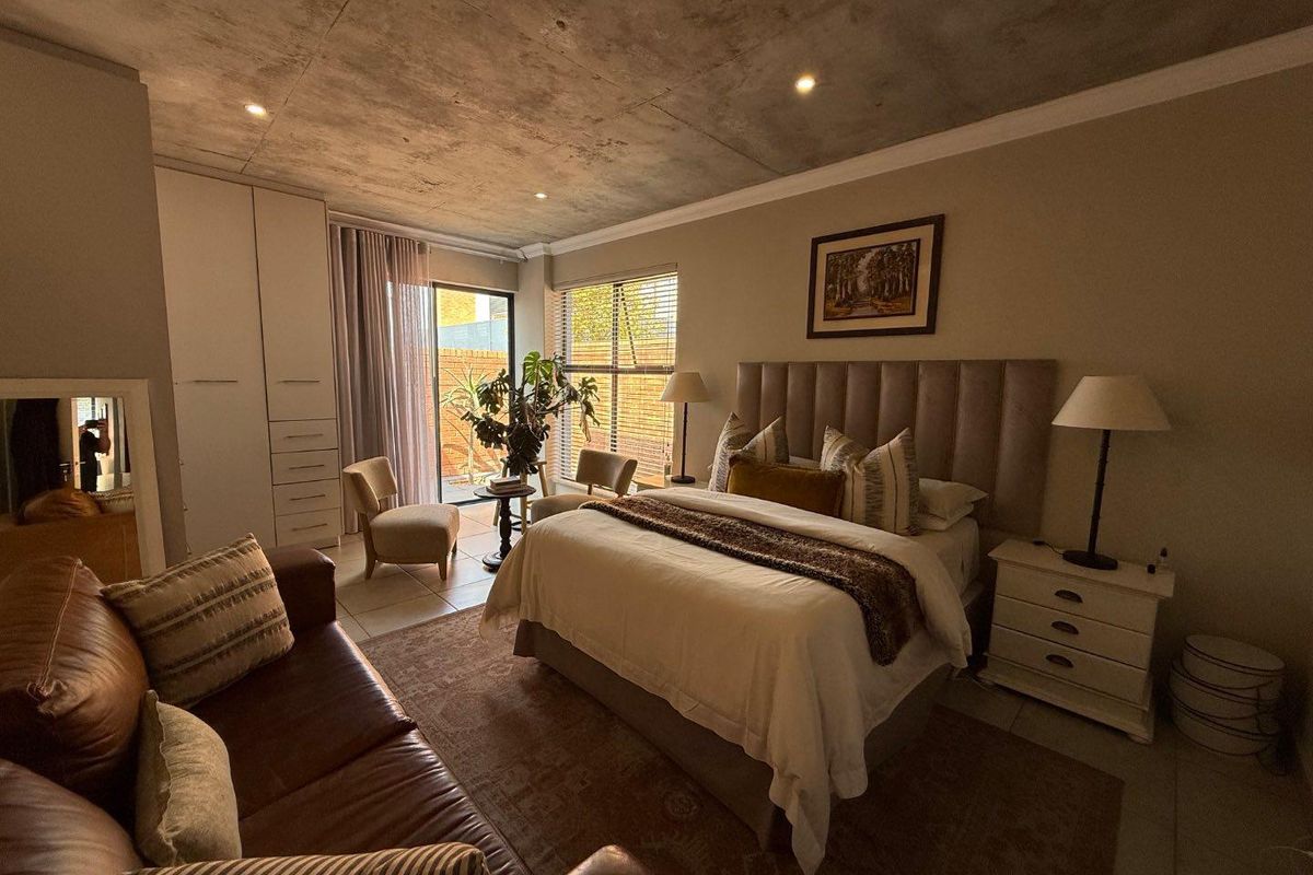 Spacious bedroom featuring an exposed concrete ceiling, built-in cabinetry, and direct access to an outdoor area through sliding glass doors.
