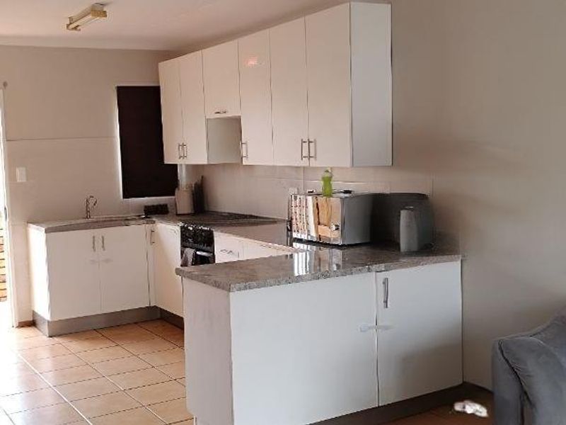A functional kitchen featuring white cabinetry, laminate countertops, a built-in oven, and tiled flooring, offering a clean and practical workspace.