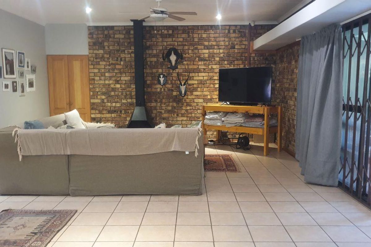 Spacious living room featuring a prominent face-brick feature wall, a built-in fireplace, and large sliding doors leading to the outdoor area.