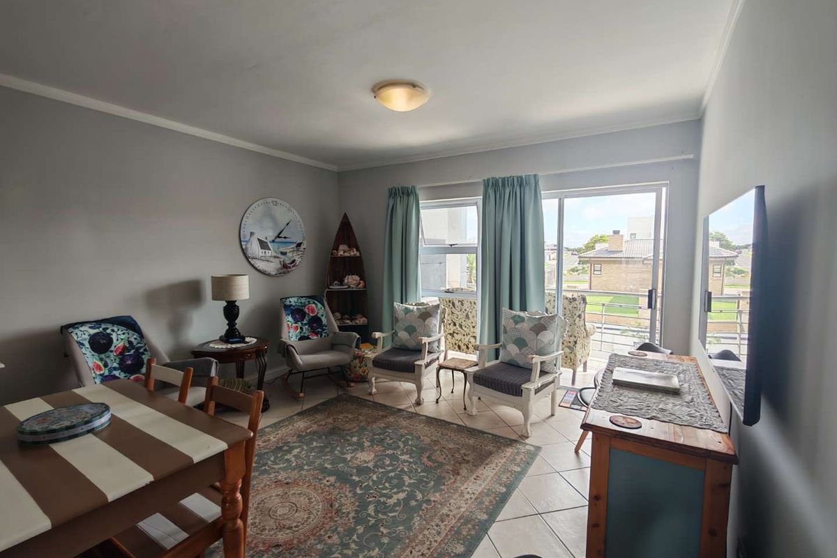 A bright living area featuring tiled flooring, large sliding glass doors leading to a balcony, and neutral wall finishes.