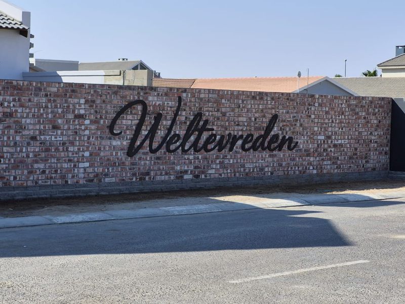 Street view of the Weltevreden estate entrance featuring a prominent brick boundary wall with custom metal signage.