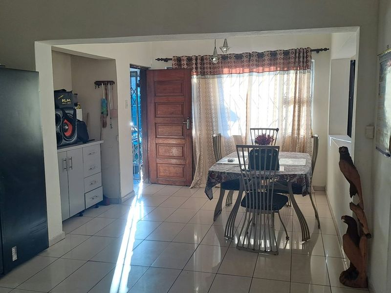 Open plan living and dining area featuring tiled flooring, built-in cabinetry, and direct access to an exterior entrance.