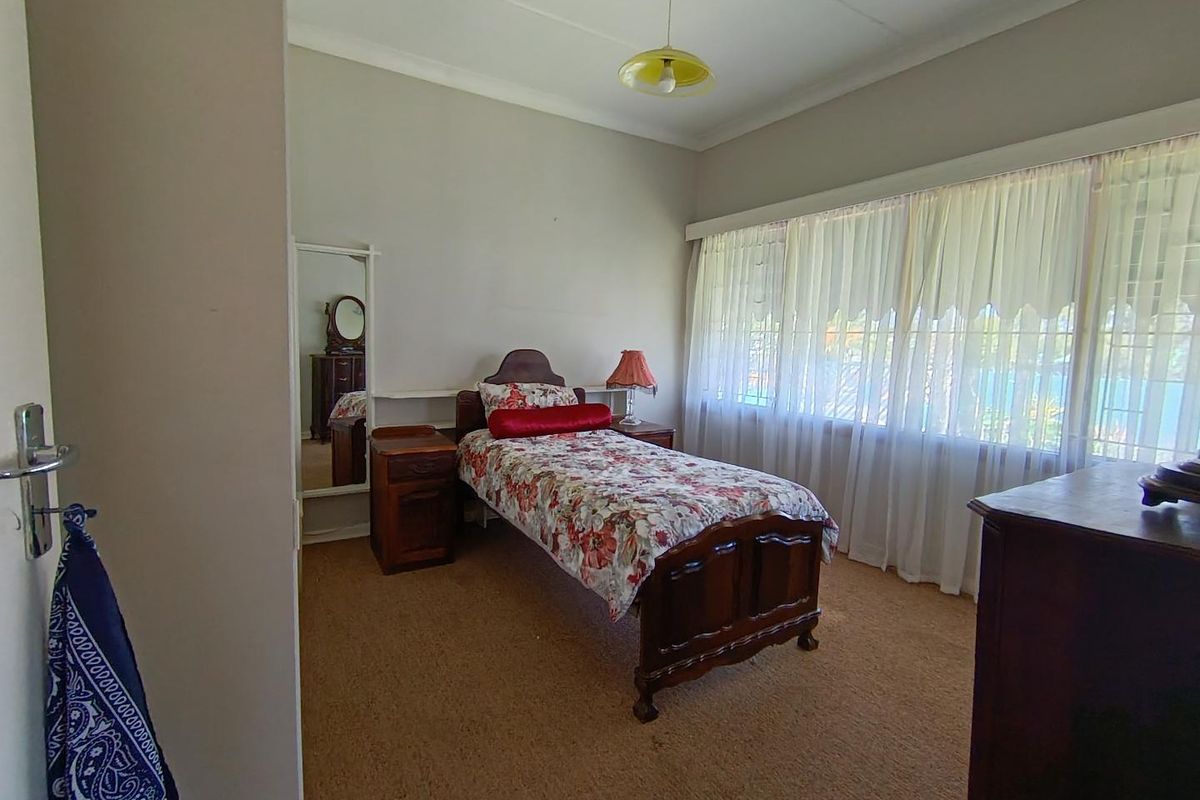A functional bedroom featuring carpeted flooring, a large window with natural light, and built-in shelving.