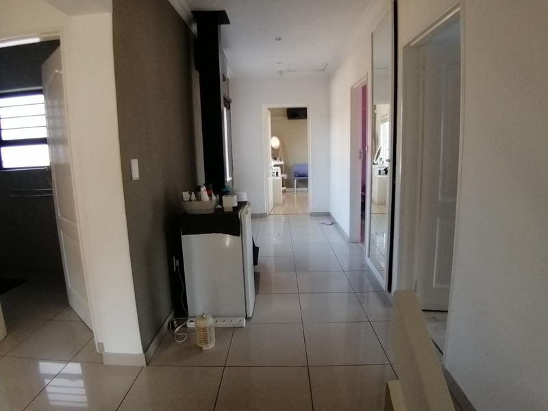 A bright, tiled hallway providing access to multiple rooms, featuring neutral wall tones and integrated mirror paneling.