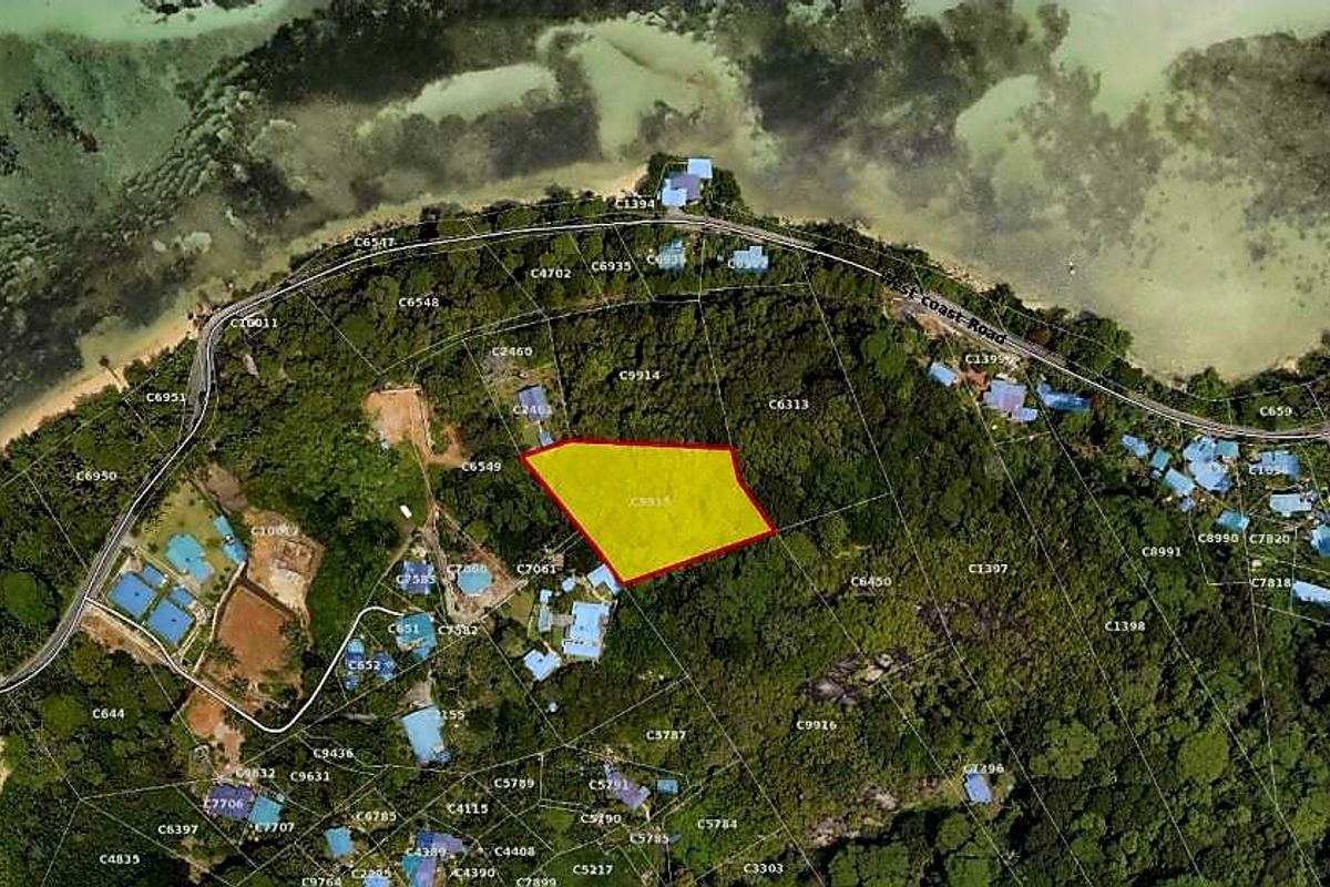 An aerial view showing the designated residential land parcel with highlighted boundaries, situated within a coastal landscape.