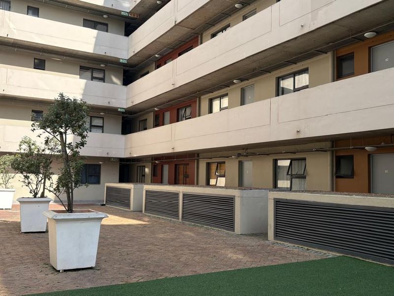 A view of the multi-story apartment complex courtyard featuring paved flooring, concrete building facades, and fixed ventilation structures.