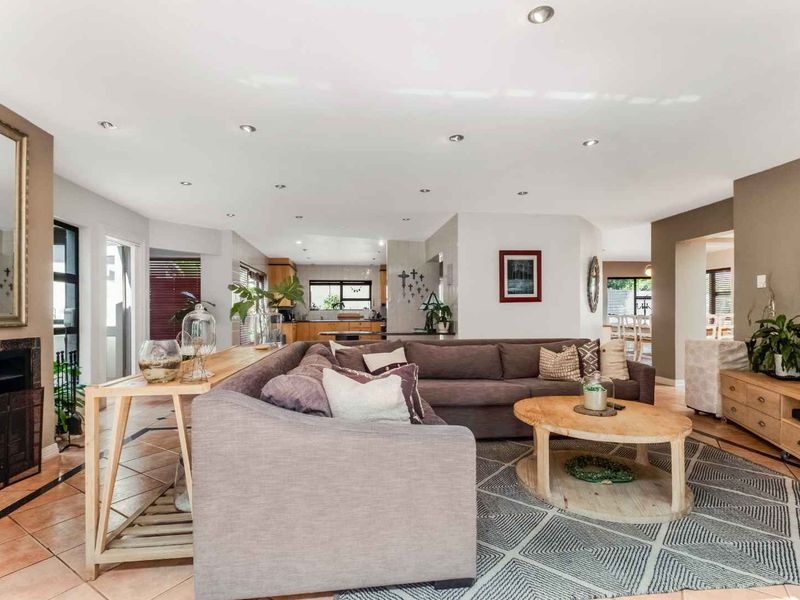 Spacious open-plan living area featuring tiled floors, recessed lighting, and a built-in fireplace, seamlessly flowing into the kitchen and dining space.
